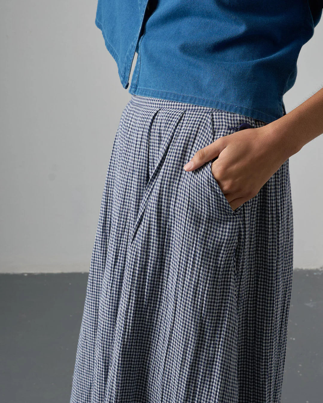 Person wearing a blue top and checkered pants against a gray background