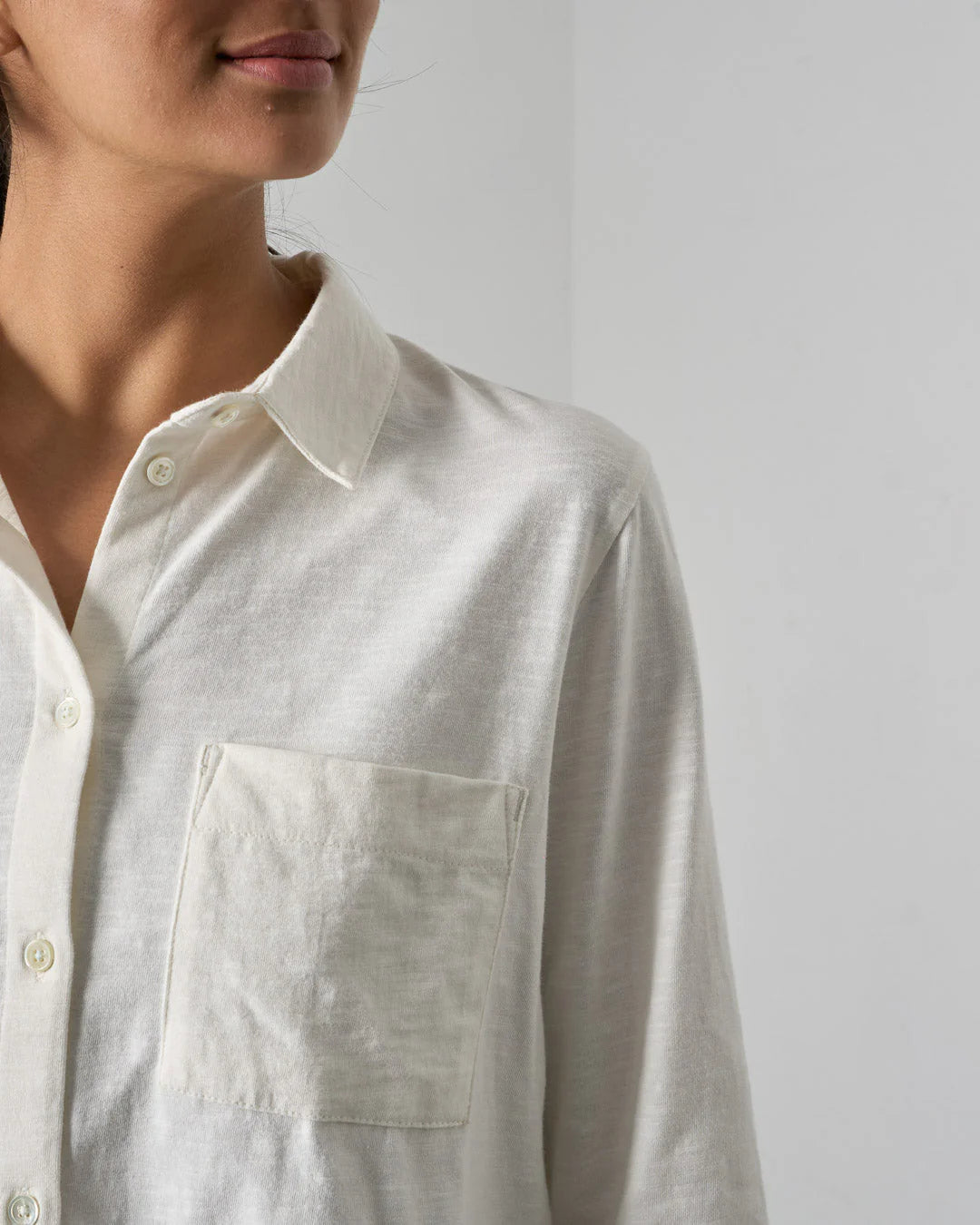 Close-up of a person wearing a light-colored shirt against a plain background