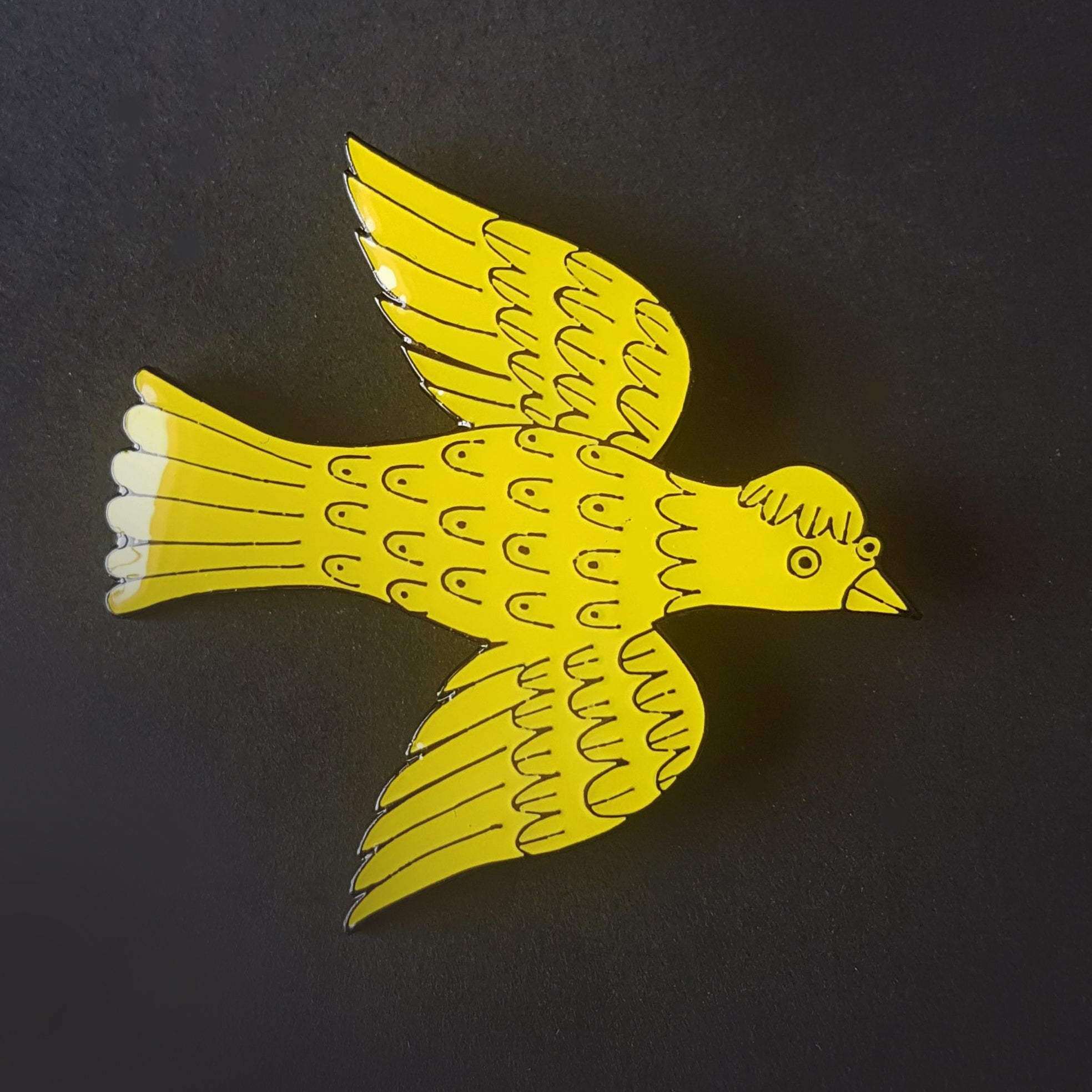 Yellow bird-shaped enamel pin with black outlines, detailed wings, and a stylized tail.
