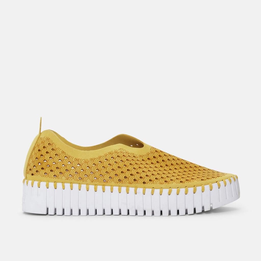 Mustard yellow slip-on shoe with a white, ridged sole and a repeating wave pattern cut-out design.