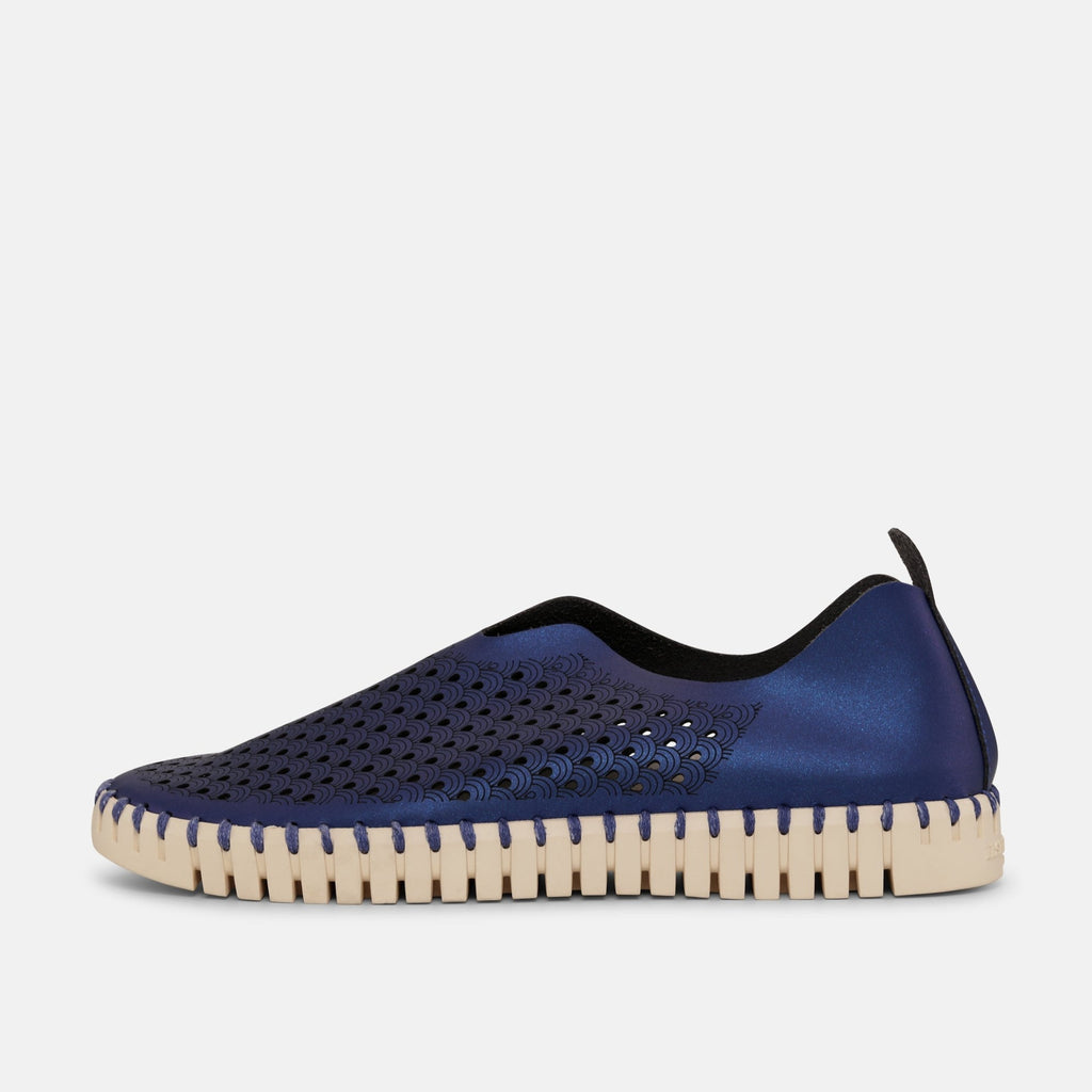 Navy blue slip-on shoe with cream sole, featuring a perforated pattern and subtle shimmer.