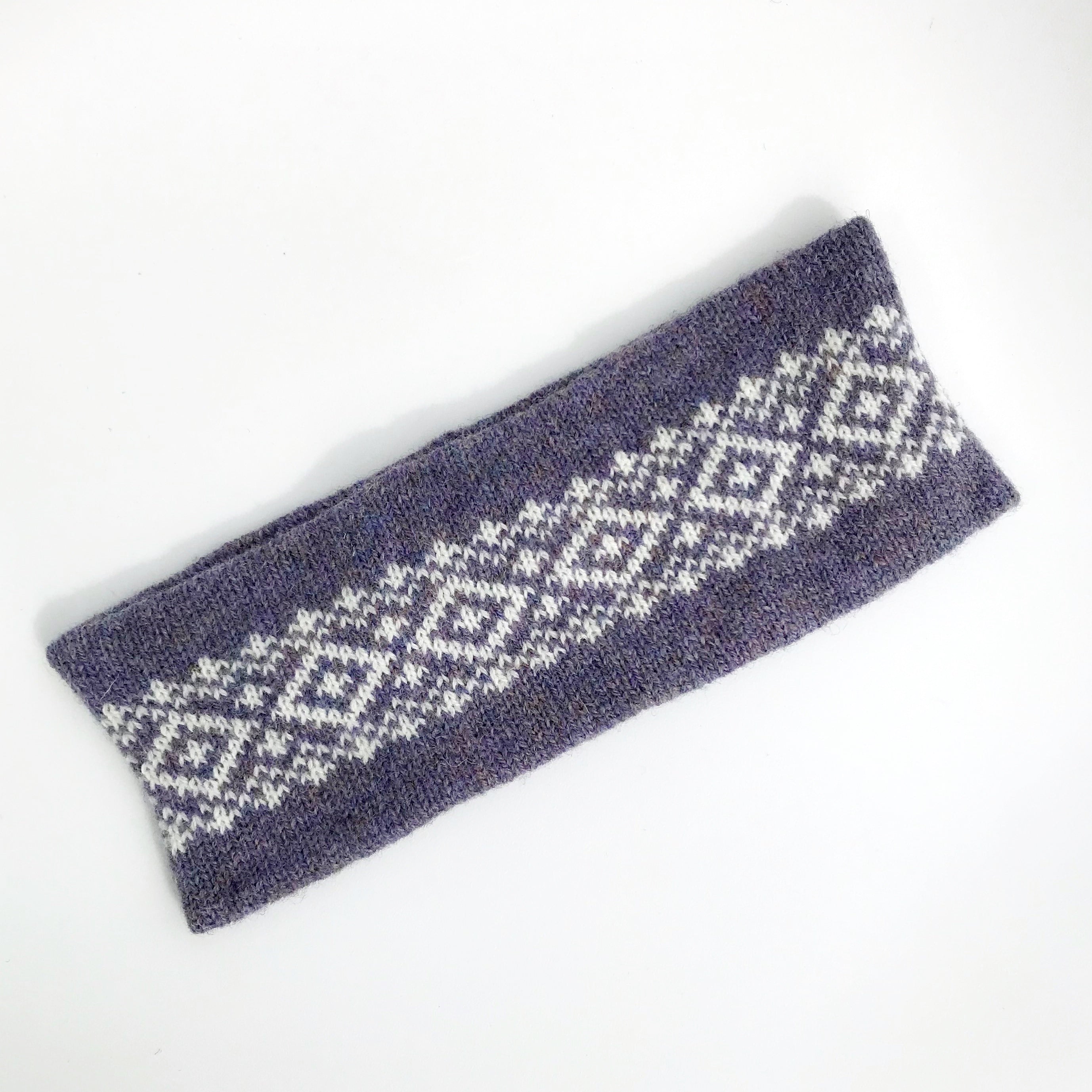 Purple knitted headband with a white geometric pattern.