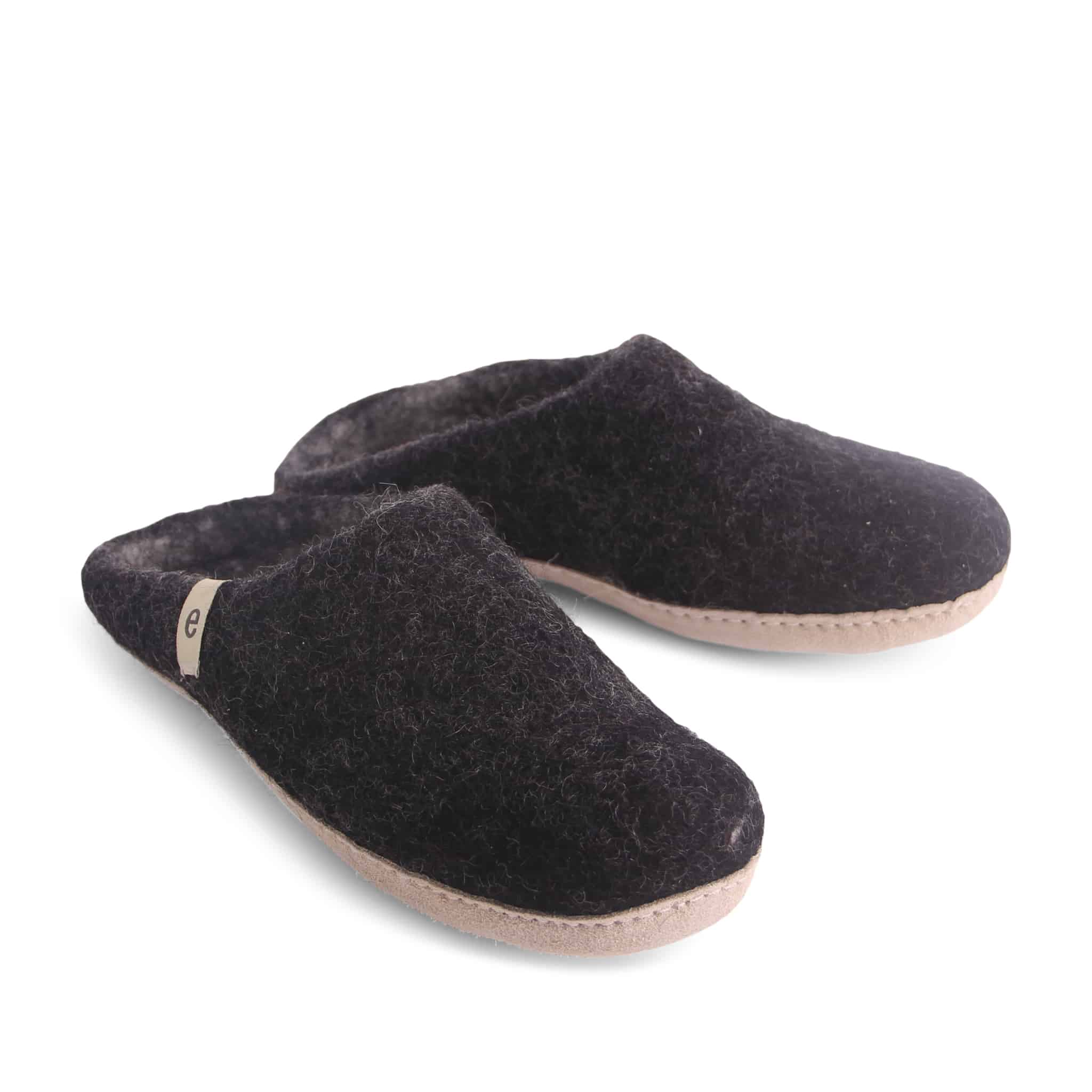 Pair of dark gray wool felt slippers with light tan soles.  A small logo is visible on one slipper.