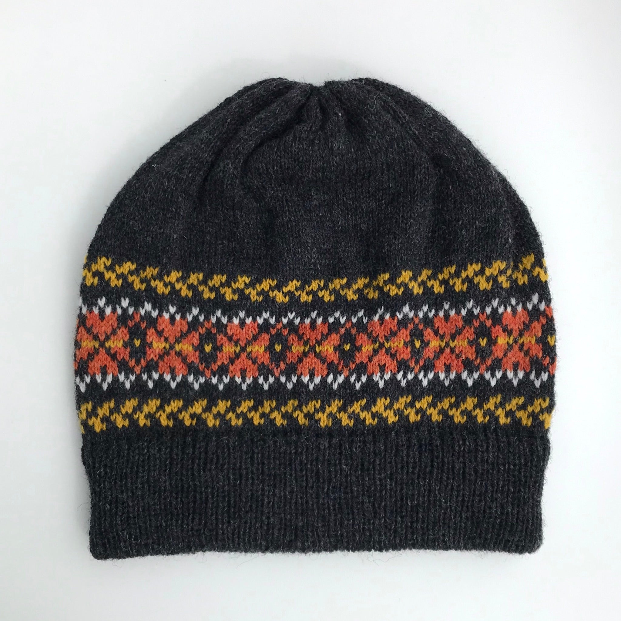 Dark gray wool beanie with a Fair Isle-style band featuring orange, white, and mustard yellow geometric patterns.
