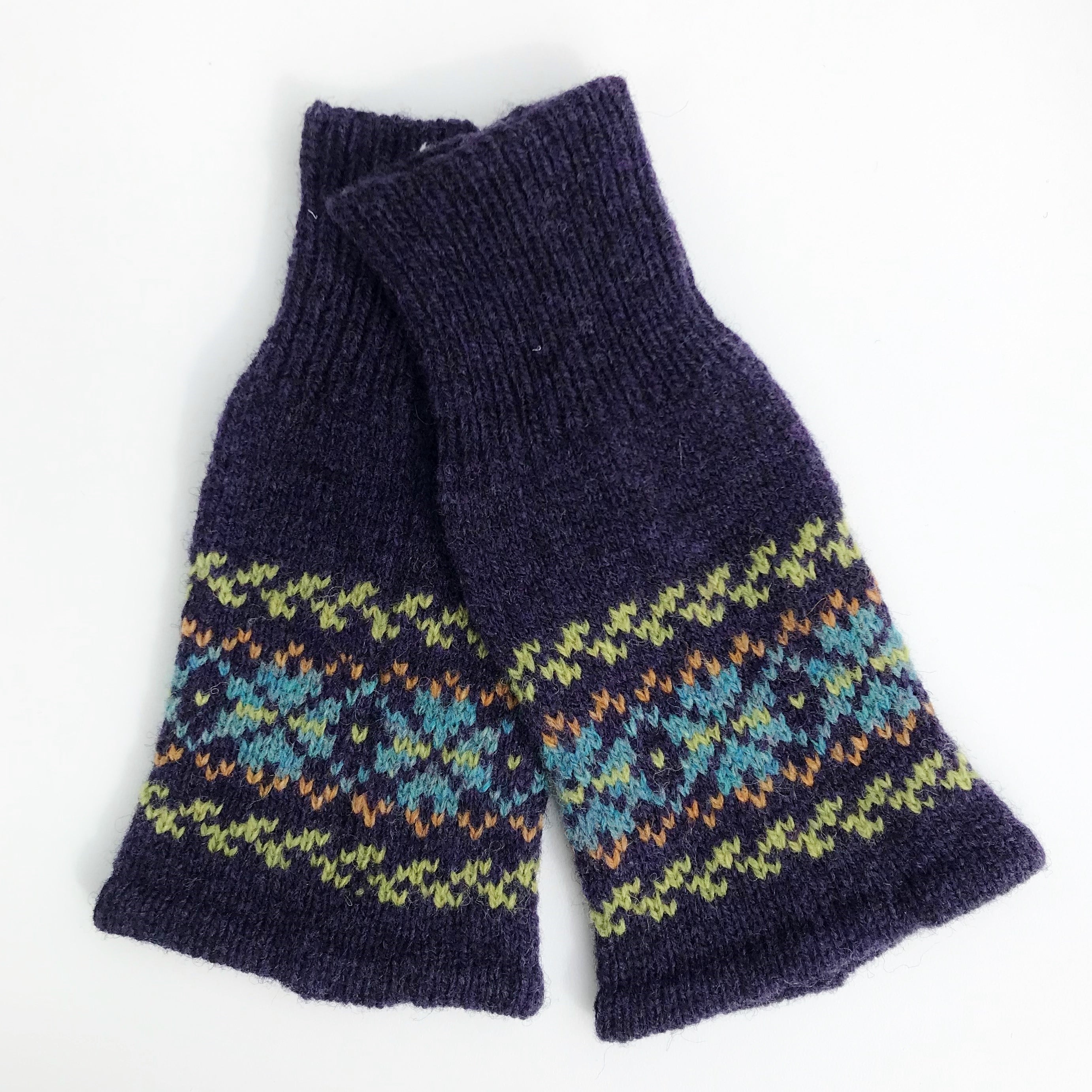 A pair of purple haze fair isle wrist warmers with geometric patterns, knitted in a cable style.