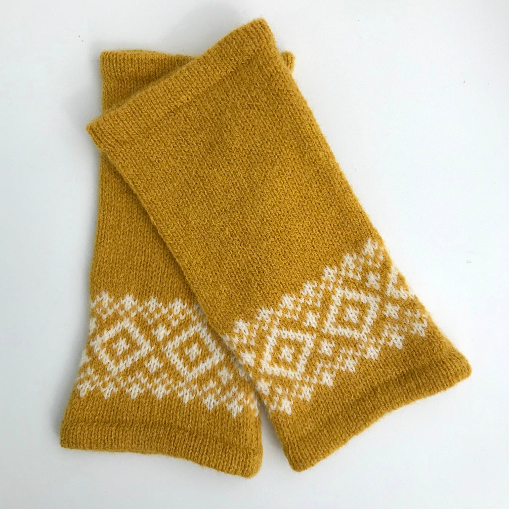 Mustard yellow knitted wrist warmers with a white Fair Isle pattern.
