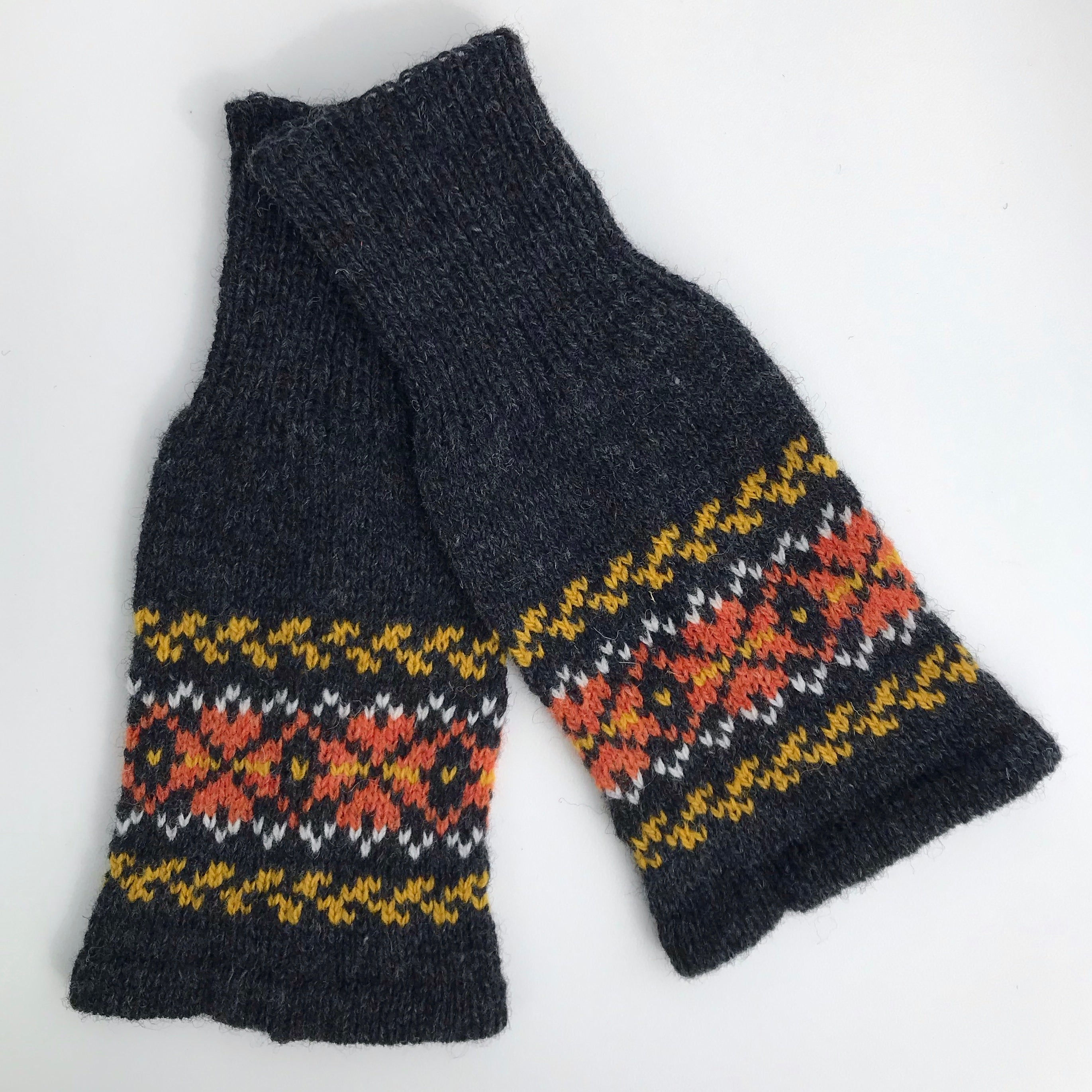 Pair of dark gray wool fingerless gloves with a colorful Fair Isle pattern in orange, white, and gold.