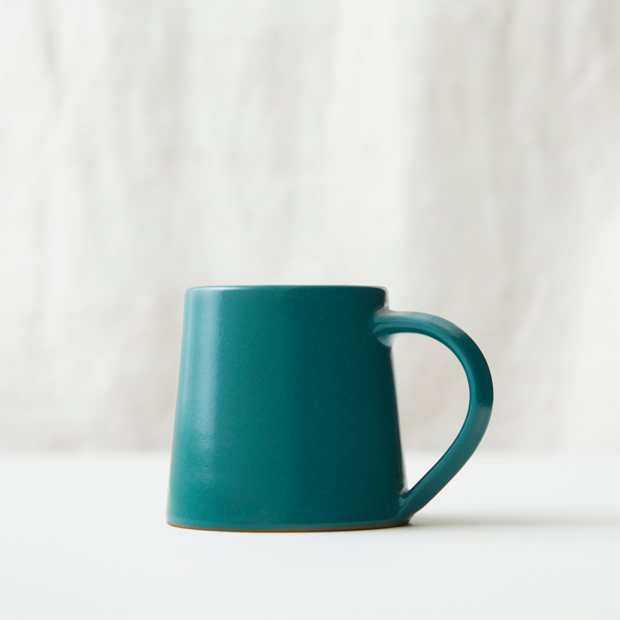 Teal ceramic mug with a slightly tapered body and a curved handle.