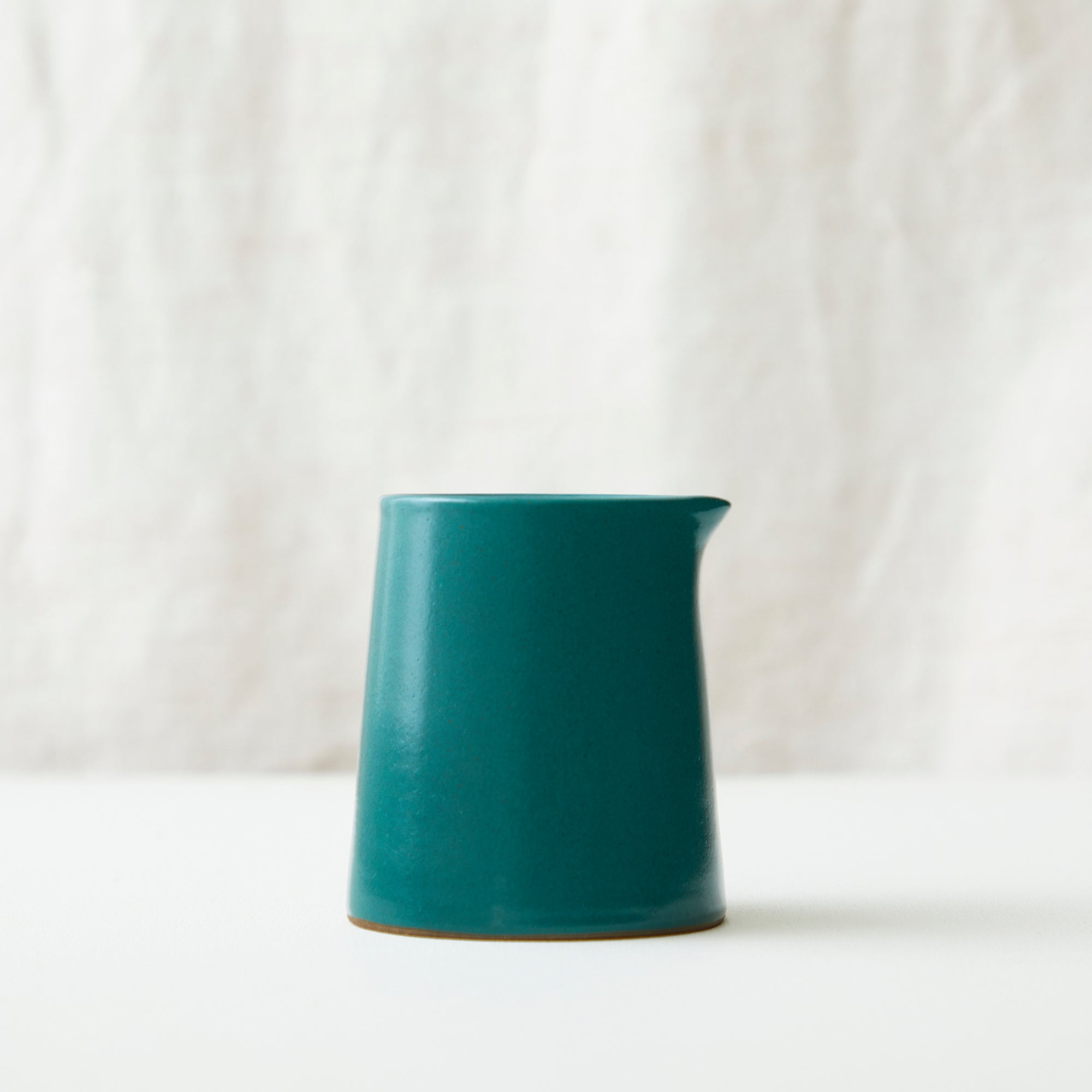 Teal ceramic creamer with a slightly tapered body and a small spout.