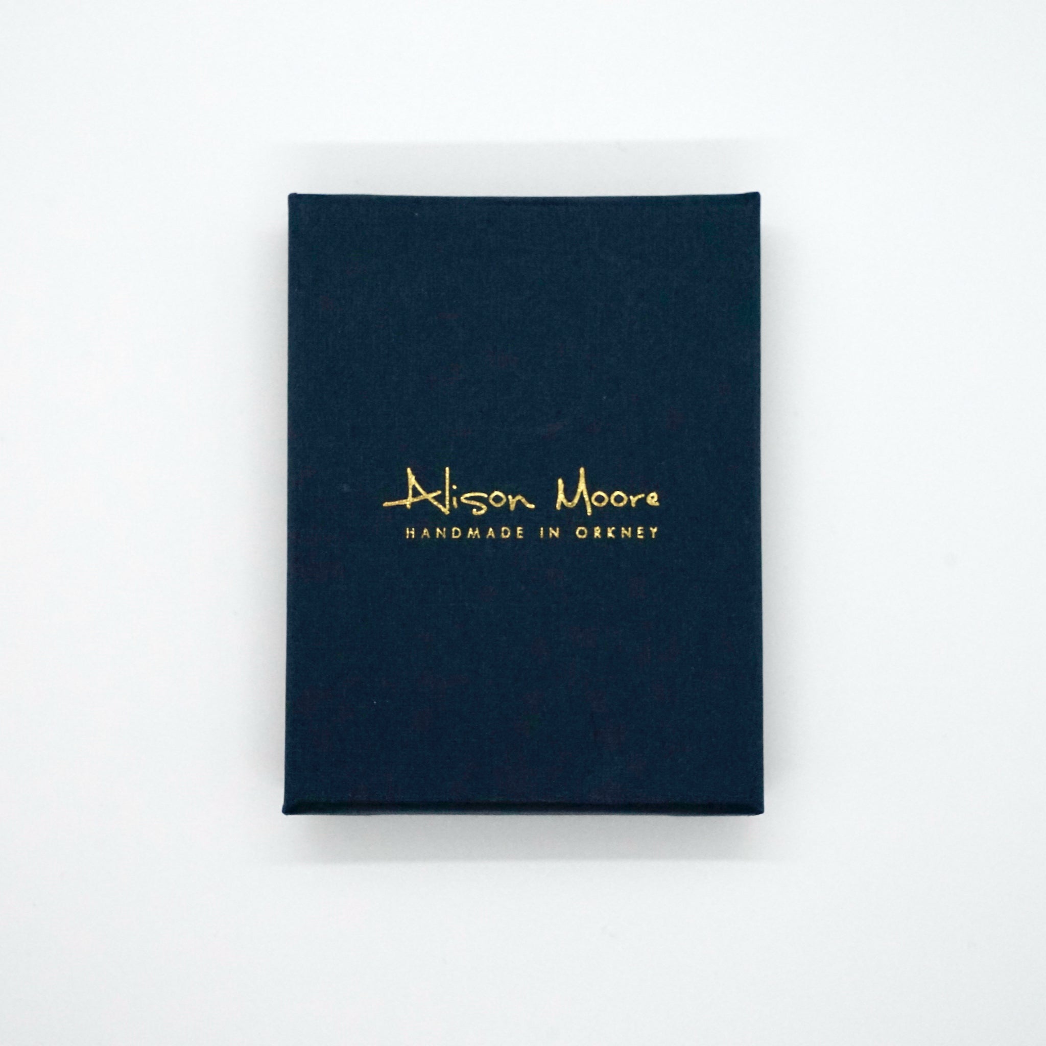 Dark blue rectangular box with gold lettering: "Alison Moore Handmade in Orkney".