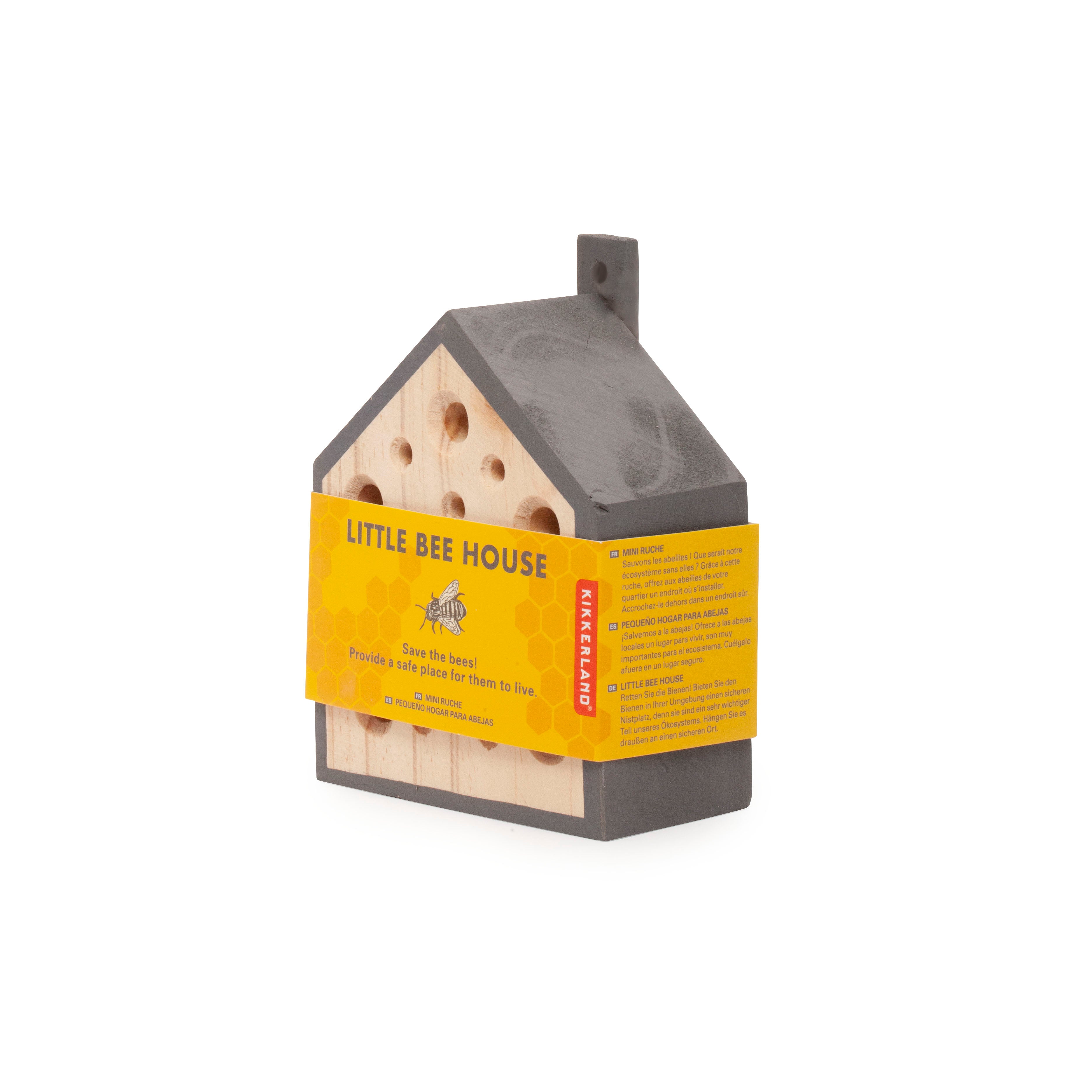 Gray and light wood house-shaped bee house with multiple holes, designed to provide shelter for bees.