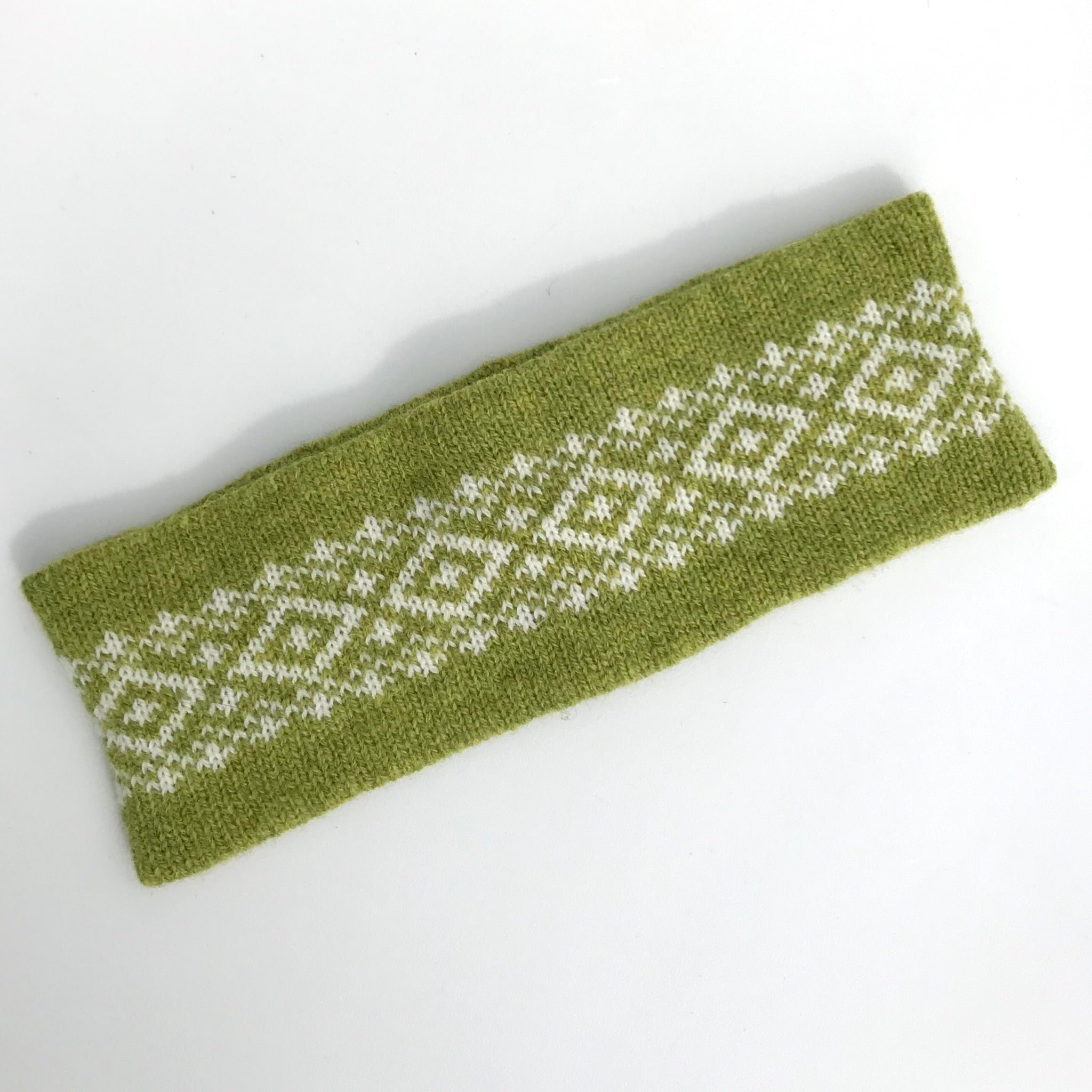 Olive green knitted headband with a white geometric pattern.