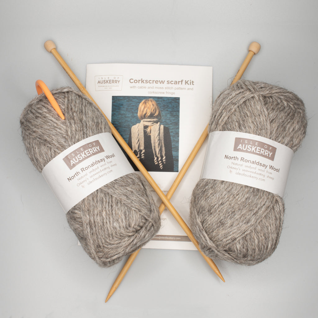 Corkscrew scarf knitting kit: two skeins of grey North Ronaldsay wool, wooden needles, and pattern instructions.