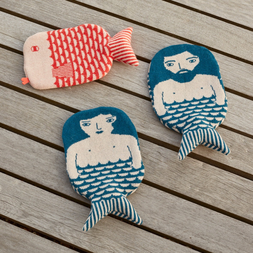 Four whimsical fish hot water bottles by Donna Wilson: red and white fish, teal mermaid with white, and striped tails.