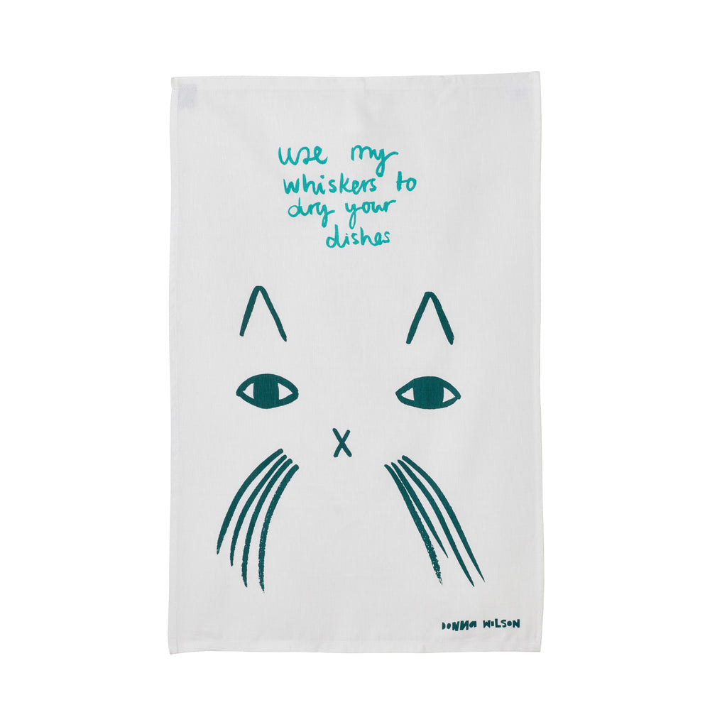 White tea towel featuring a teal cat design with the text "Use my whiskers to dry your dishes," by Donna Wilson.