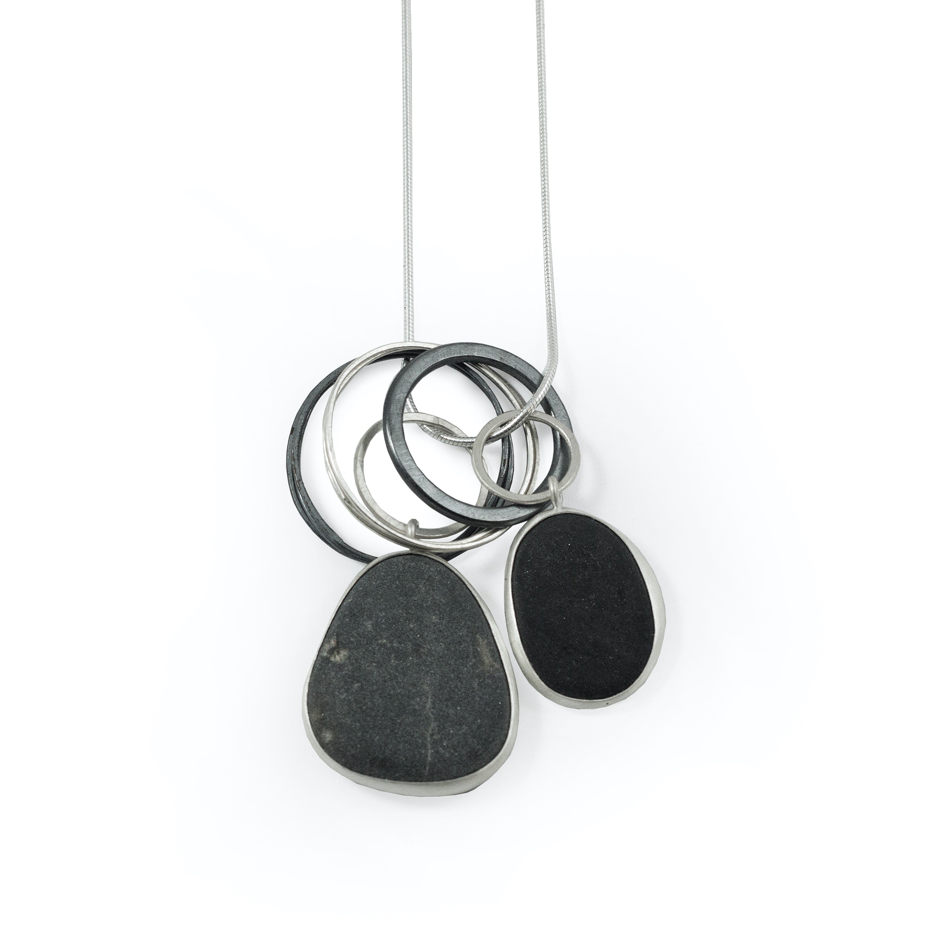 Silver necklace featuring a pendant with interlocking rings and two dark gray, oval-shaped stones.
