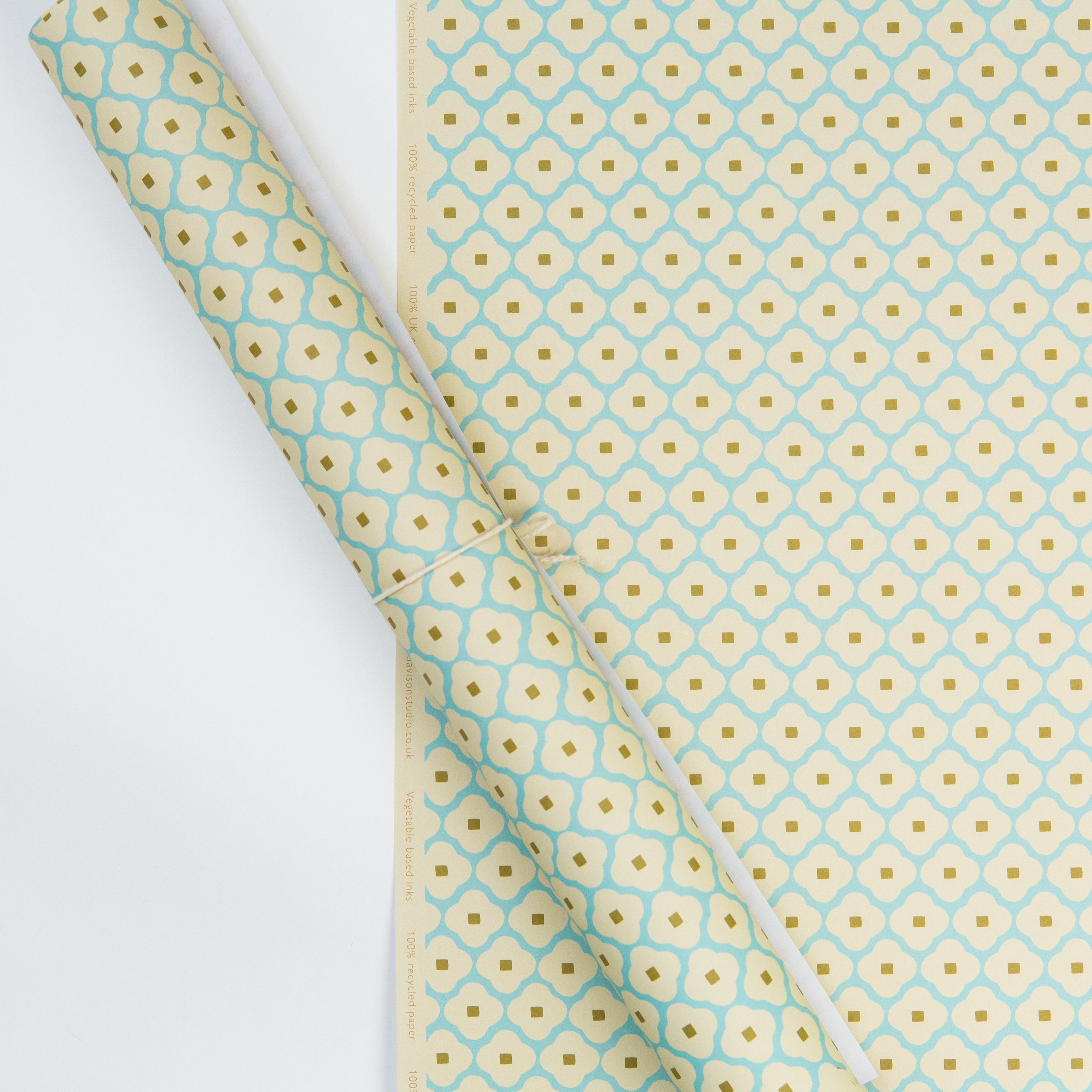 Roll of pale blue and cream patterned wrapping paper.  The design features a repeating geometric motif with gold accents.