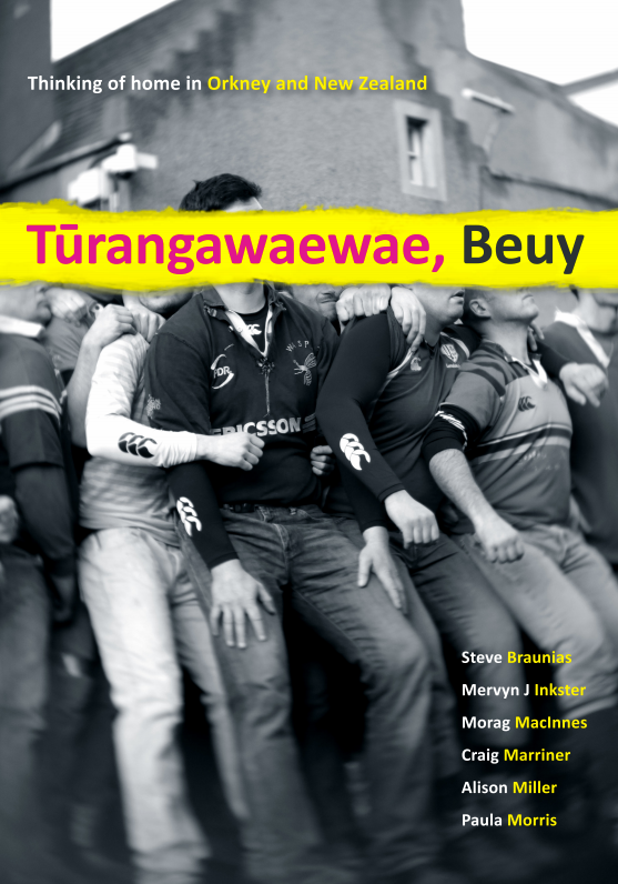 Black and white photo of a group of people huddled together, possibly a rugby team, with the title "Tūrangawaewae, Beuy"