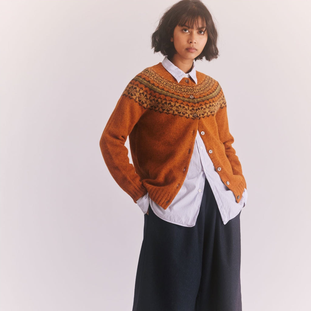 a female model standing with hands in pockets wetaing a Harley of Scotland Ladies Cardigan - Vintage Orange