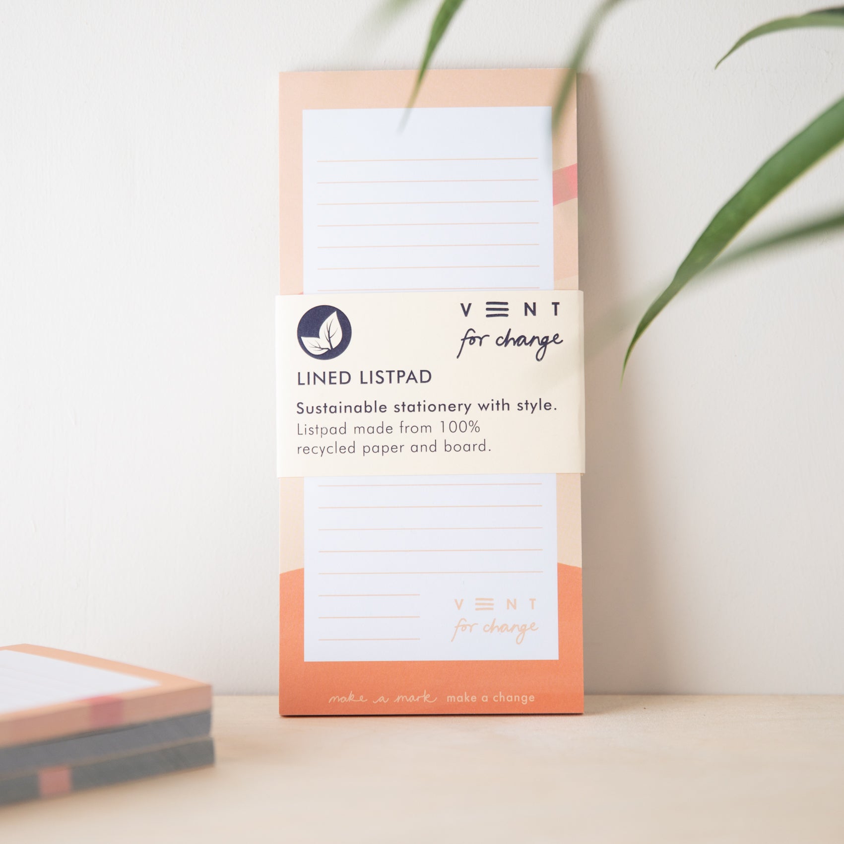 Peach-colored lined notepad made from 100% recycled paper and board. Features "Vent for Change" branding and a leaf logo.