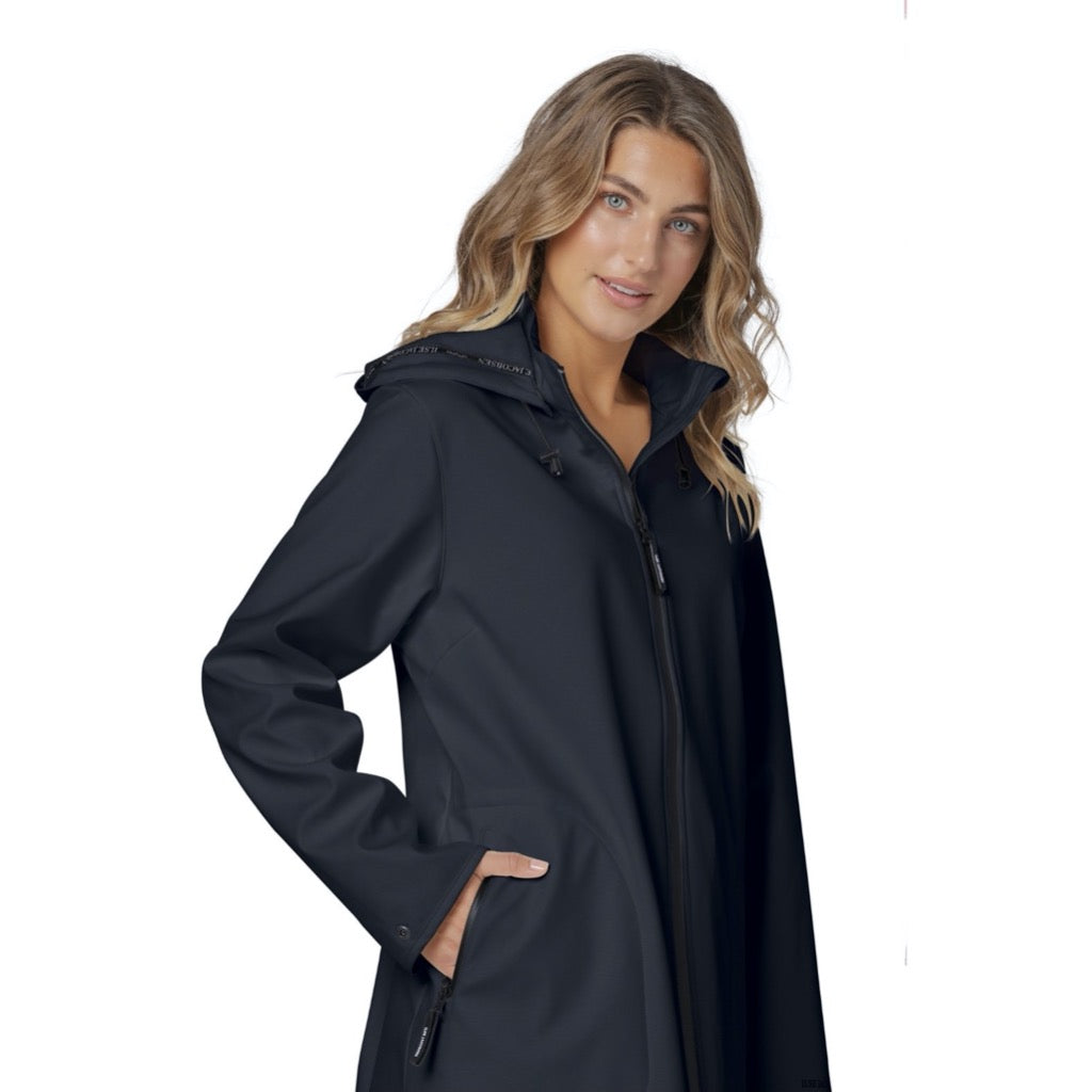 Woman in a navy blue, zip-front, hooded softshell coat with pockets. The coat has a sleek, modern design.