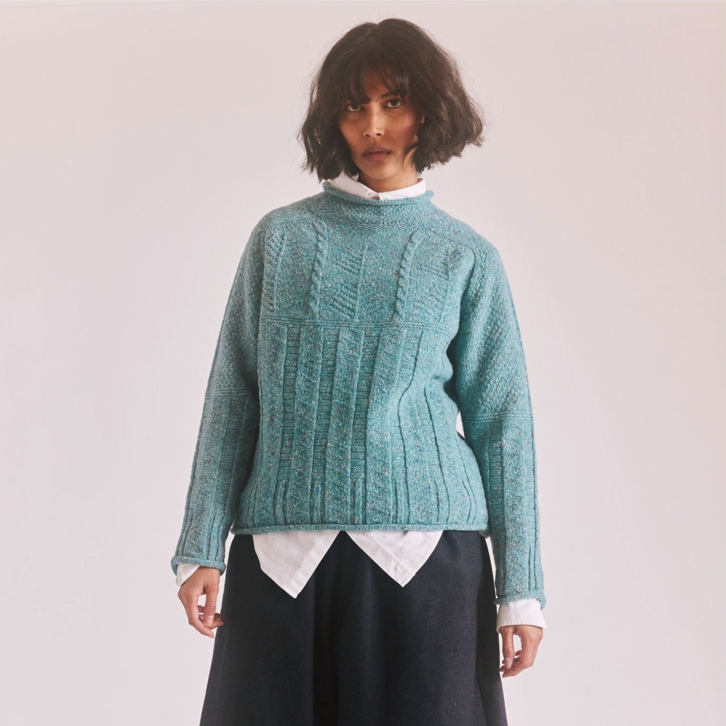 Teal cable-knit wool sweater with a high neckline and boxy fit.