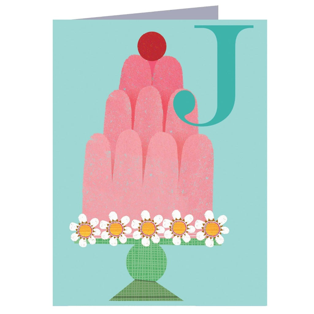 Greeting card featuring a pink layered cake decorated with daisies, atop a green stand, and a teal letter J.