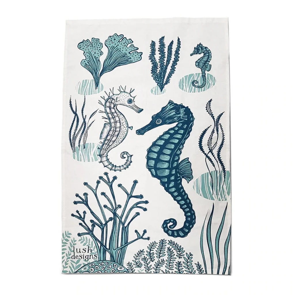 Tea towel featuring teal and white seahorses amongst stylized seaweed and coral.