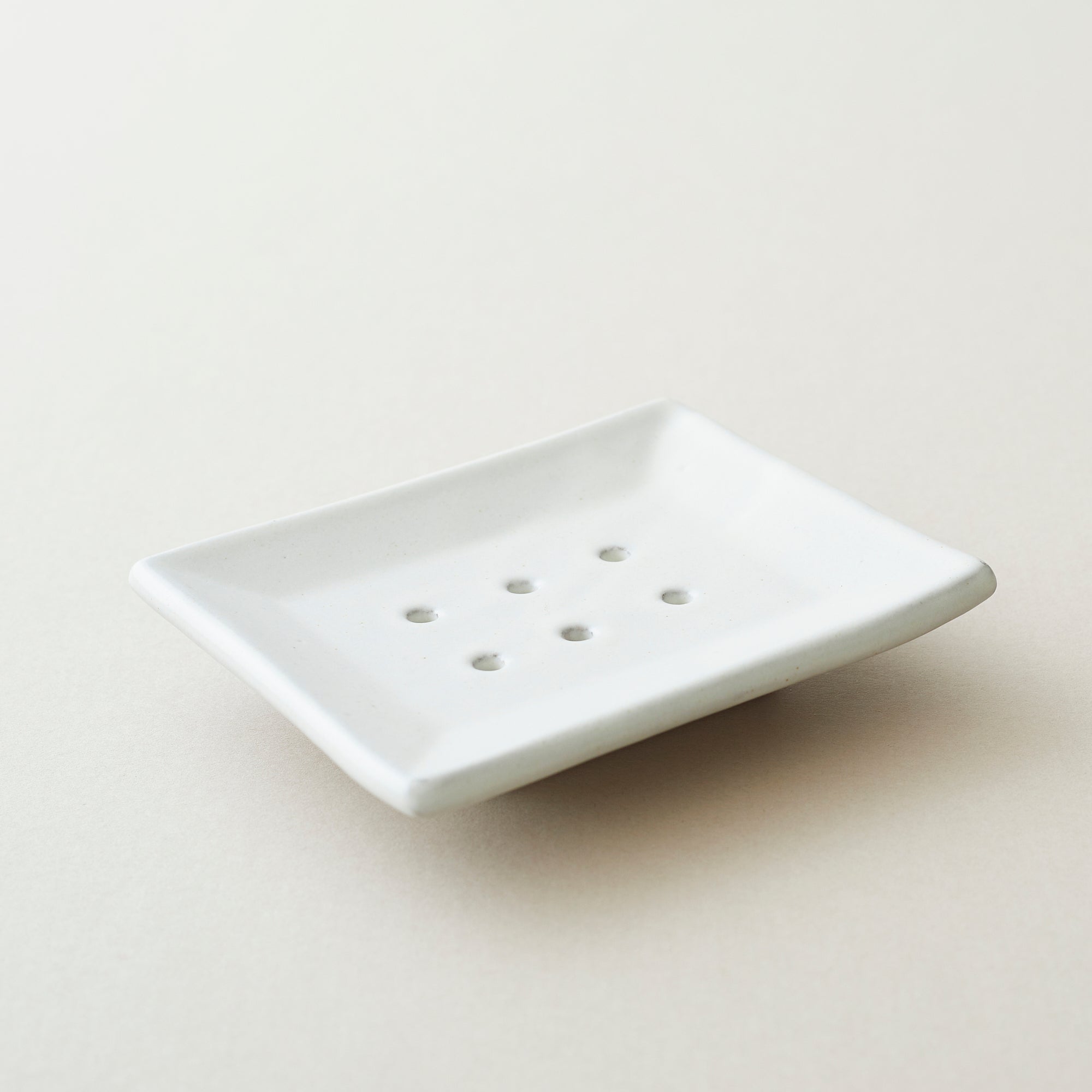 White rectangular ceramic soap dish with six drainage holes.