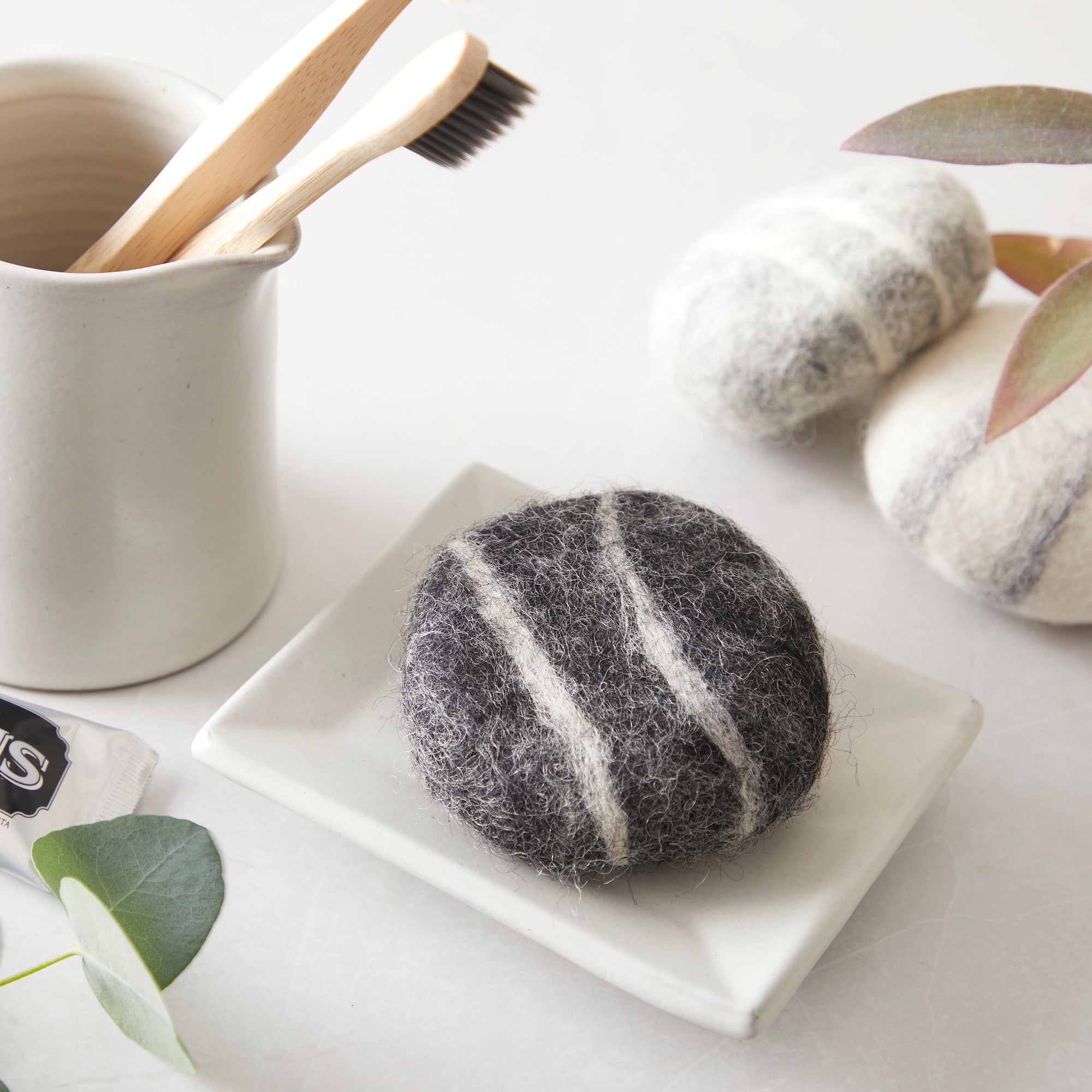 Dark gray and white felted soap on a small white dish.