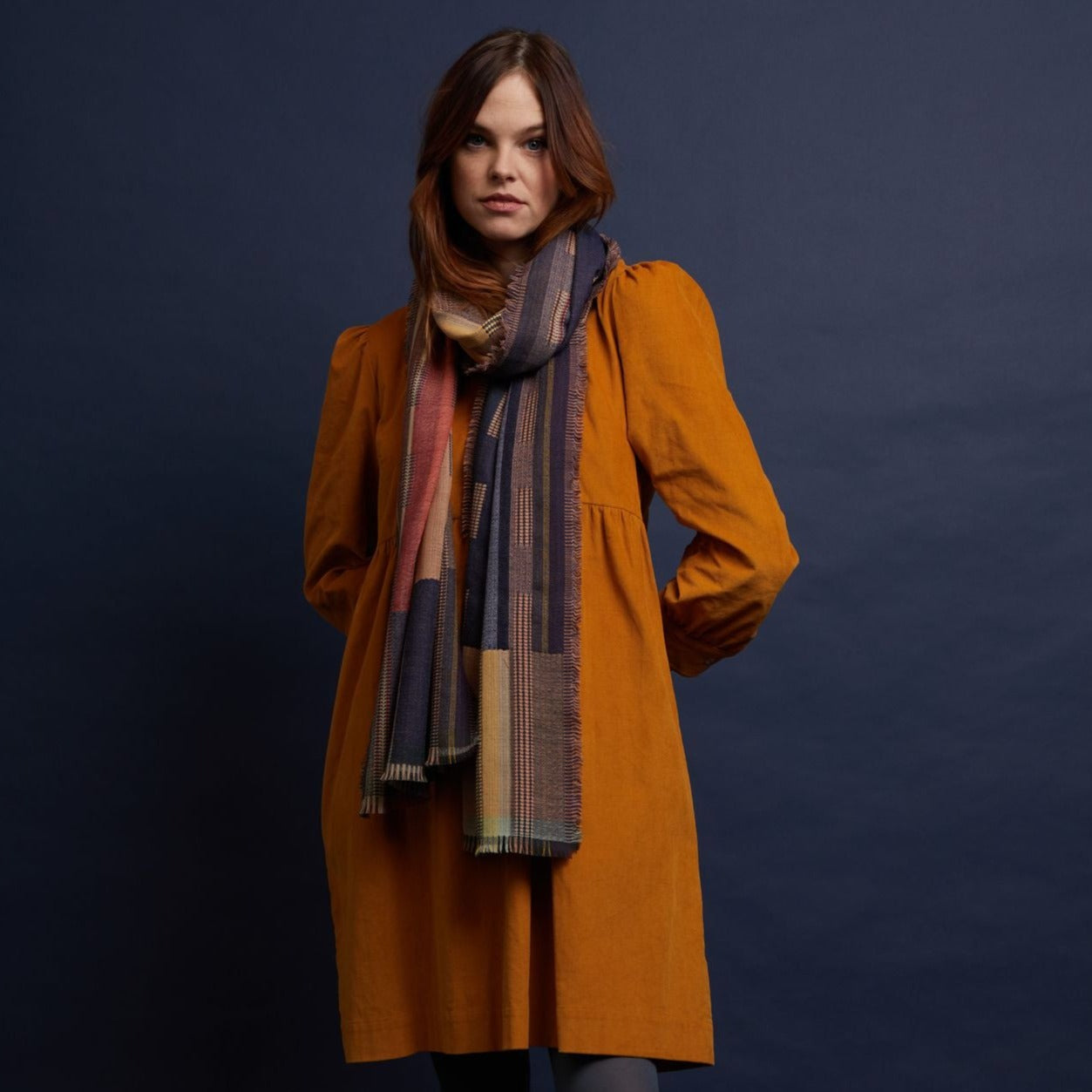 Multicolored geometric patterned scarf draped around a woman's neck.