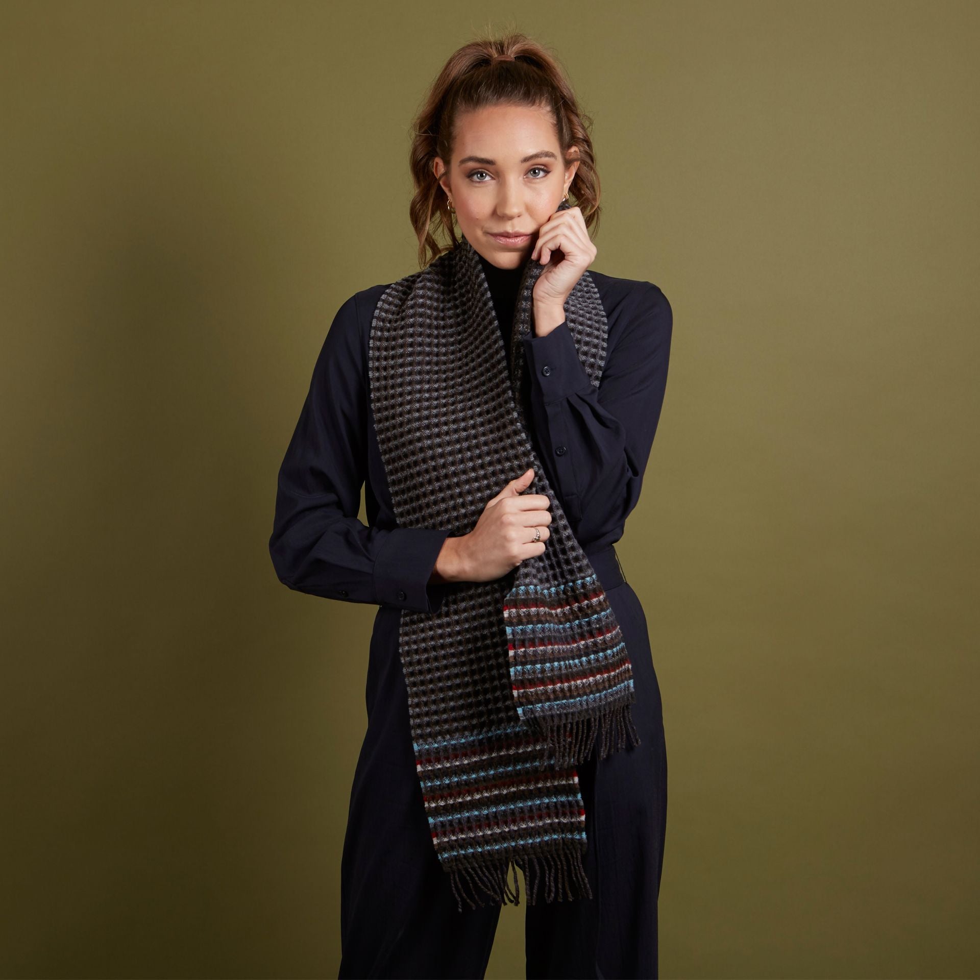 Dark gray and brown woven wool scarf with multicolored stripes and fringe.