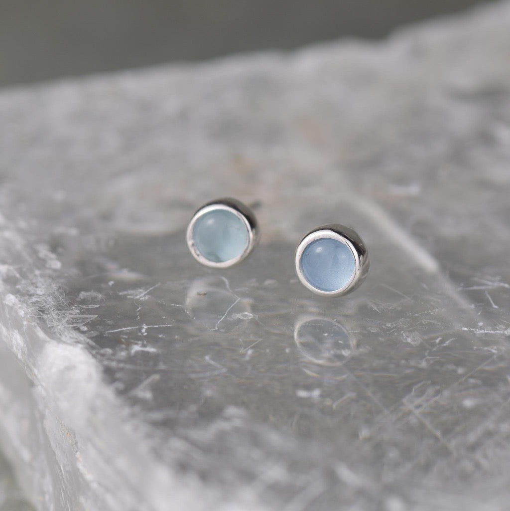 Pair of aquamarine stud earrings with silver settings.  Round cabochon stones.