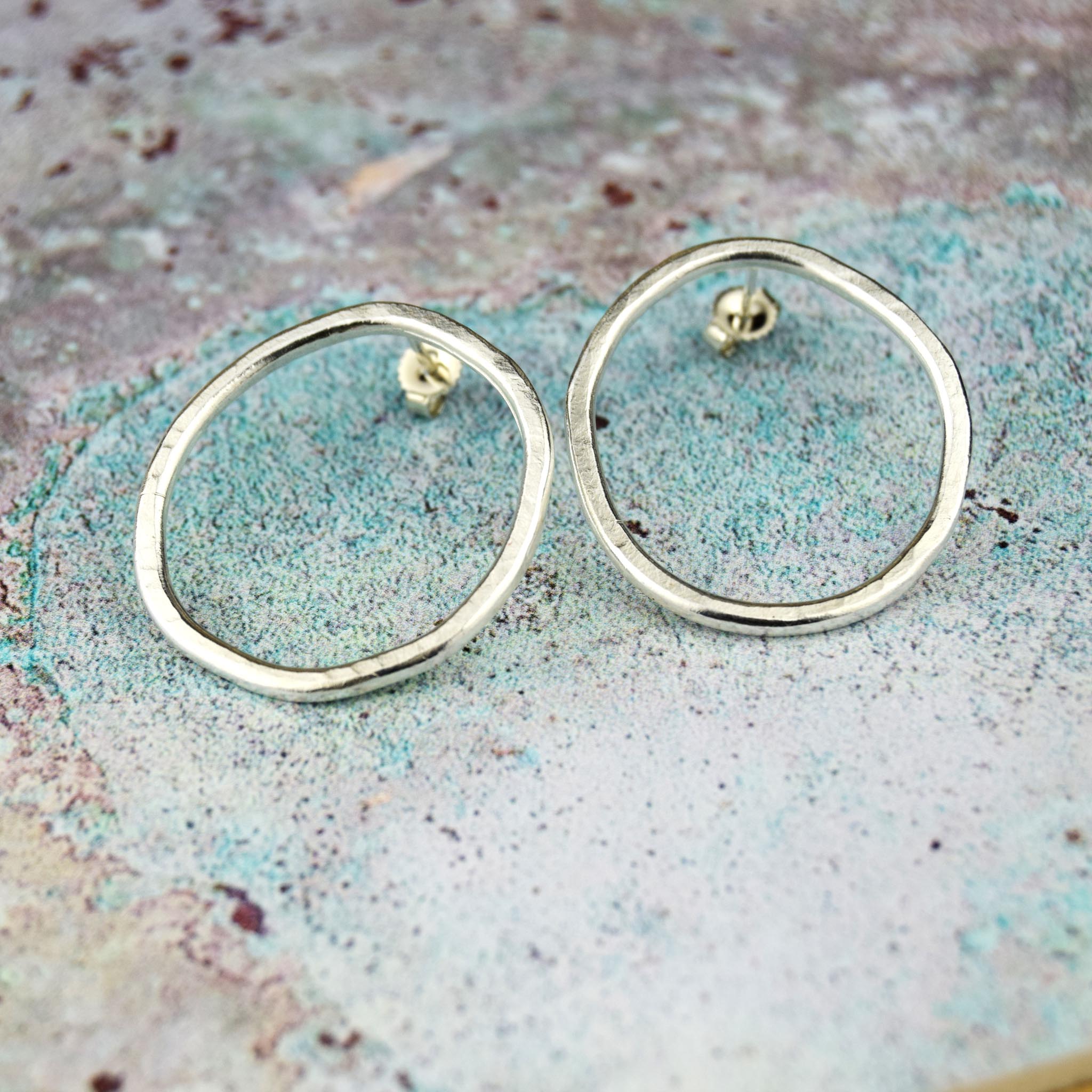 Pair of silver open circle stud earrings with a hammered texture.