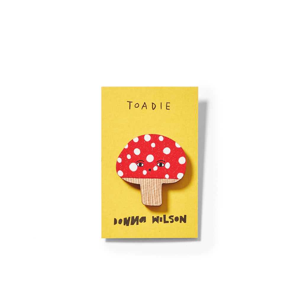 A yellow card featuring a red mushroom with white spots, labeled "Toadie," by Donna Wilson.