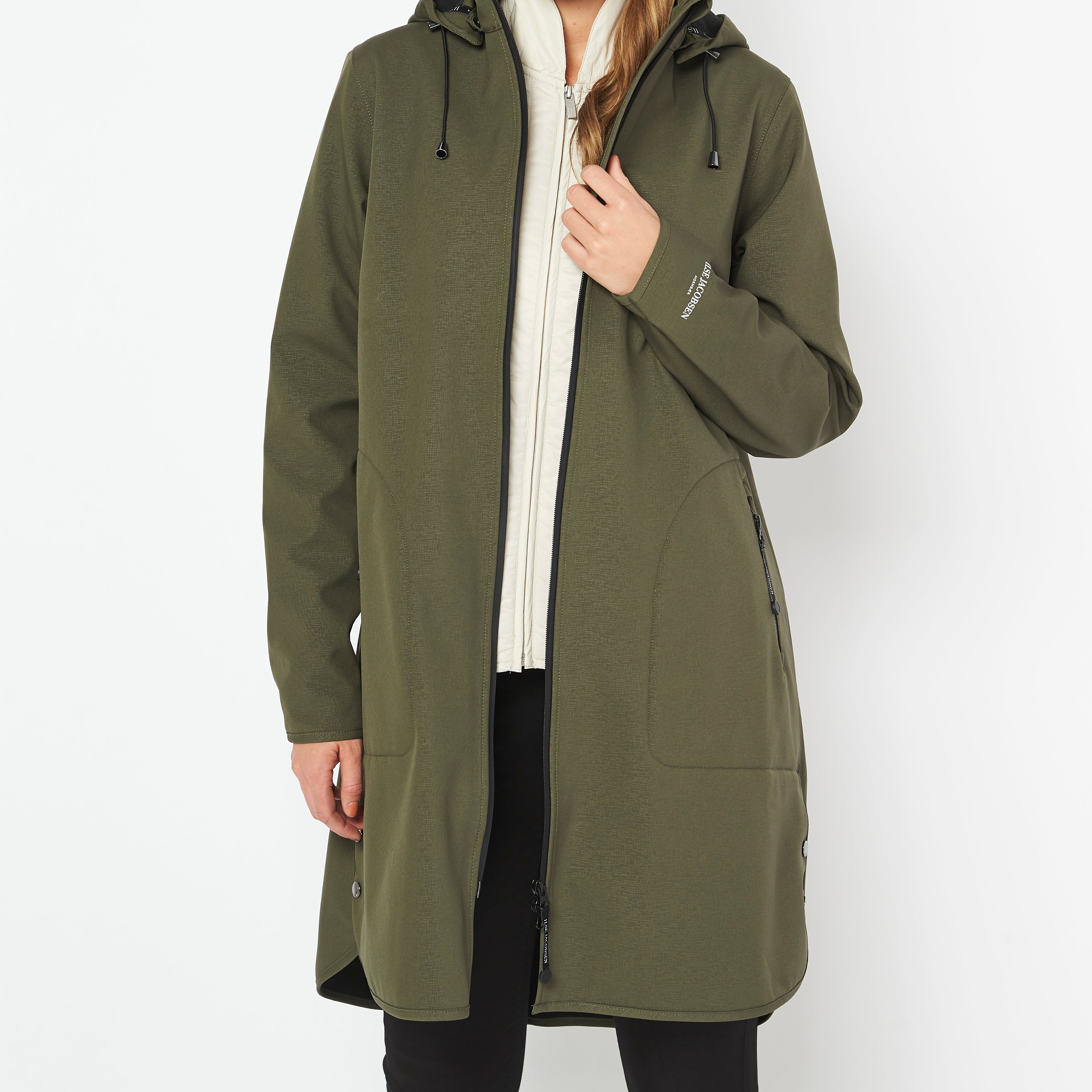 Olive green women's softshell jacket with black zipper, hood, and subtle texture. Features a slightly curved hem and discreet
