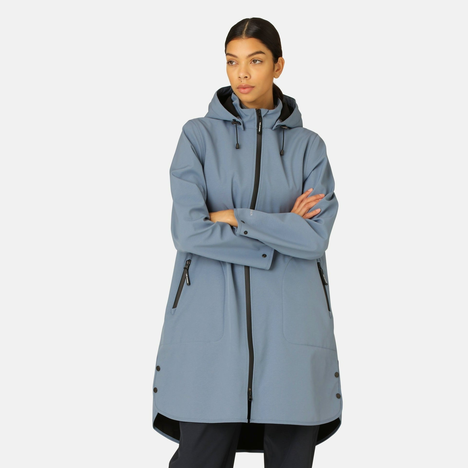 Woman in a stylish, light blue, knee-length raincoat with a hood and black zipper. The coat has a smooth texture and features