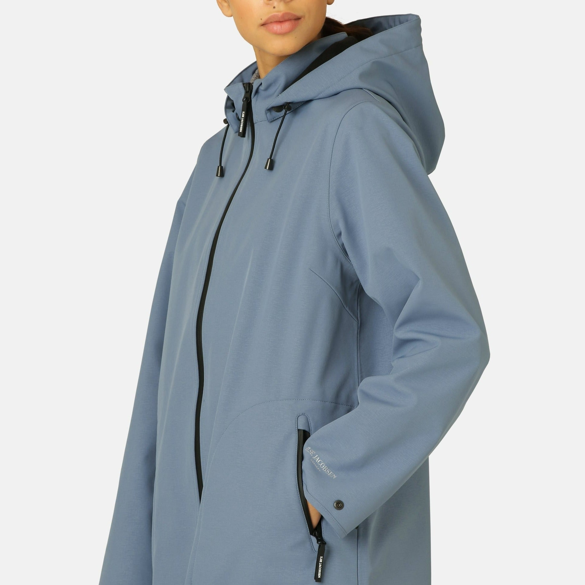 Dusty blue Else Jacobsen softshell jacket with black zipper and drawstring hood; subtle texture, side pockets.