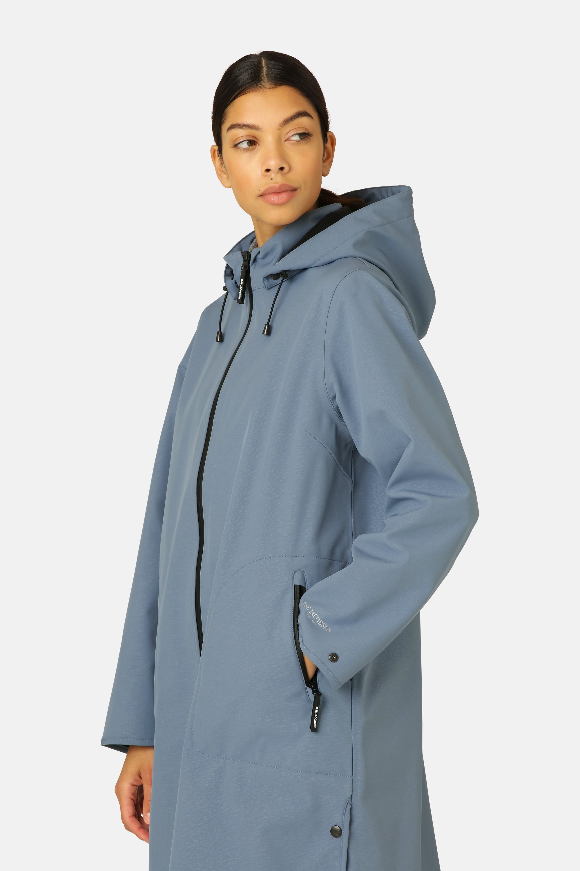 Dusty blue, long Ilse Jacobsen raincoat with a hood and black zipper. The coat has a subtle texture and features a discreet
