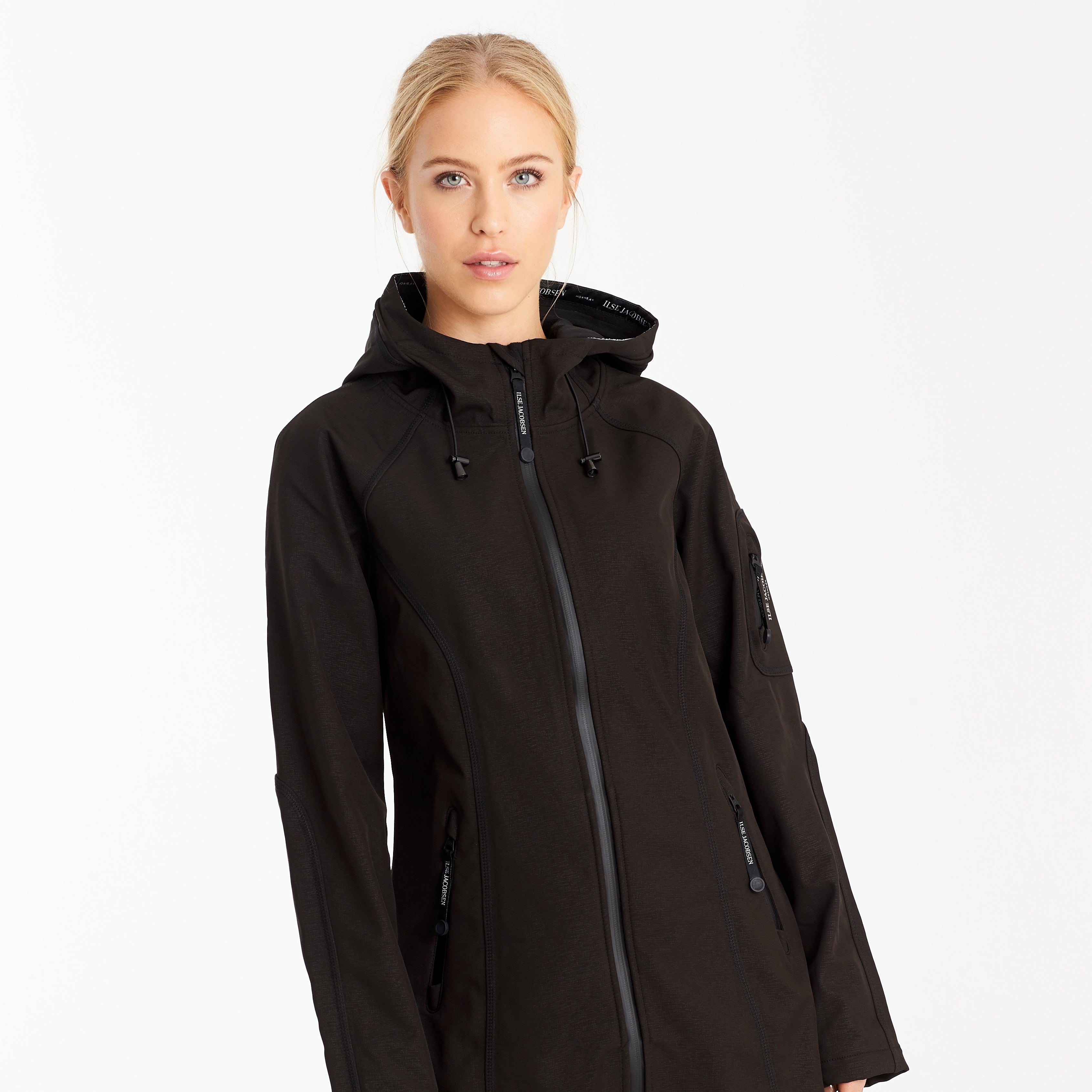 Black Ilse Jacobsen Softshell hooded jacket with zipper closure, subtle texture, and brand label detailing. Model shown wearing.