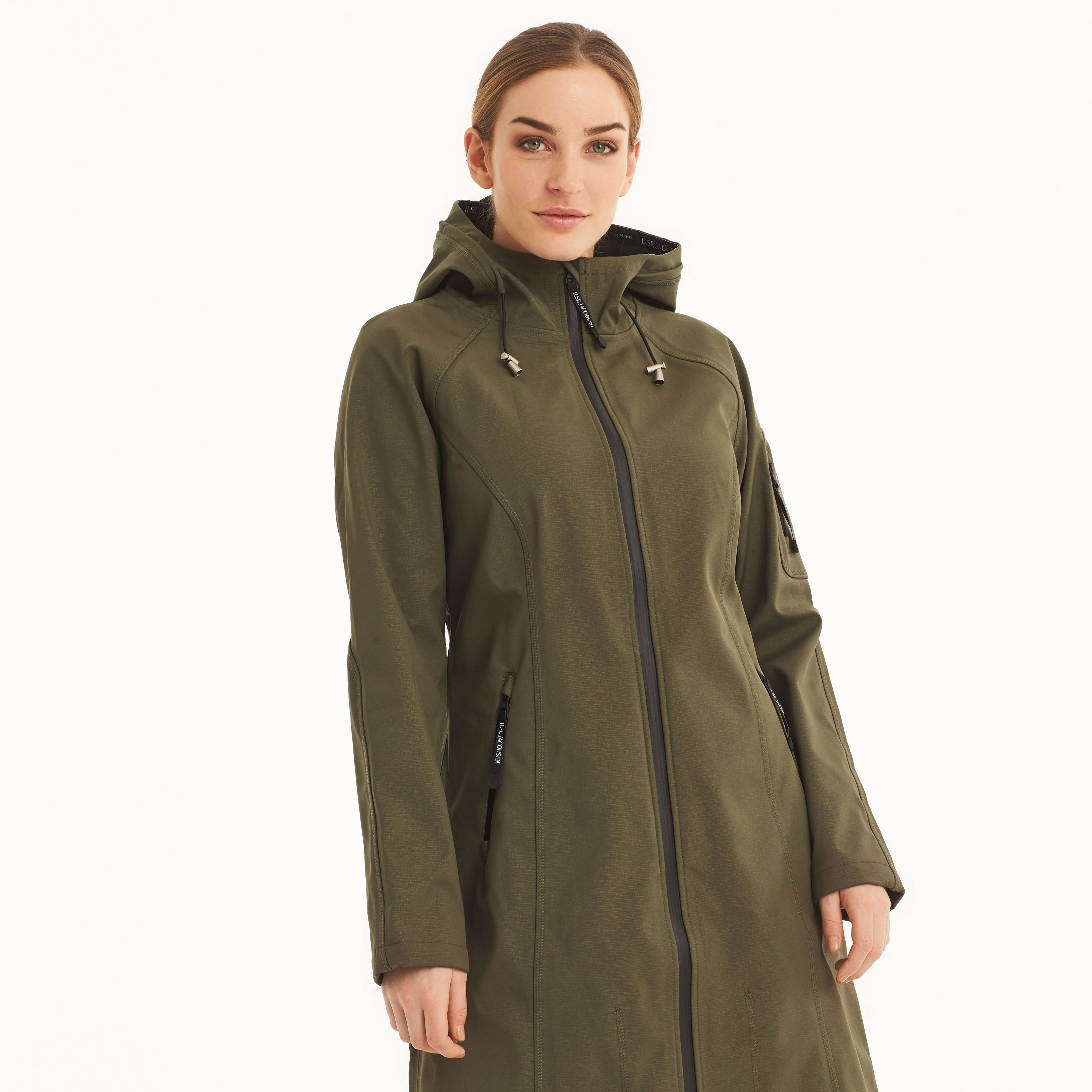 Olive green Ilse Jacobsen Hornbæk Softshell long coat, featuring a full-length zip, hood, and subtle texturing. Model showcases