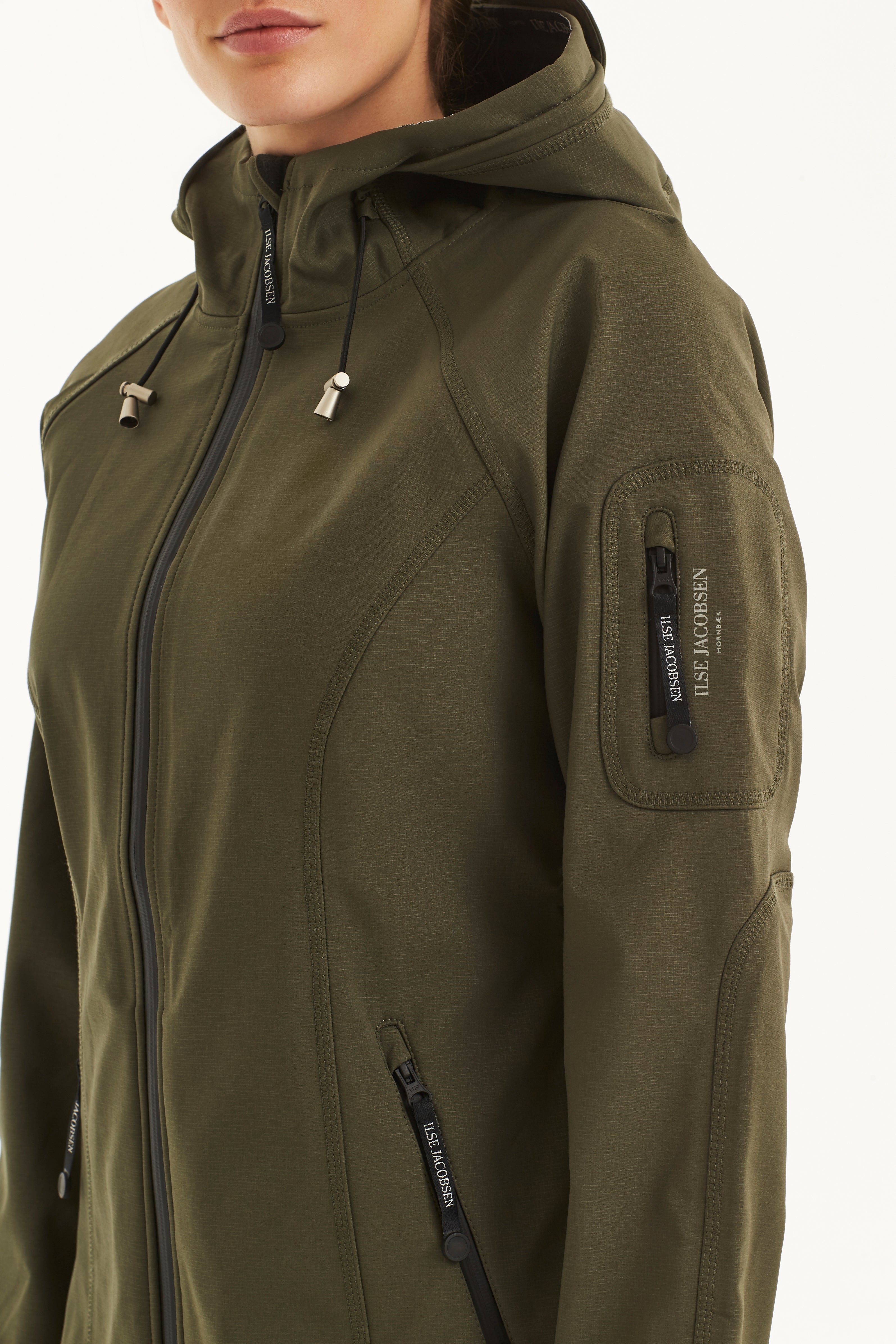 Olive green Ilse Jacobsen Hornbæk softshell jacket, close-up showing textured fabric, black zipper, and branded zipper pulls.