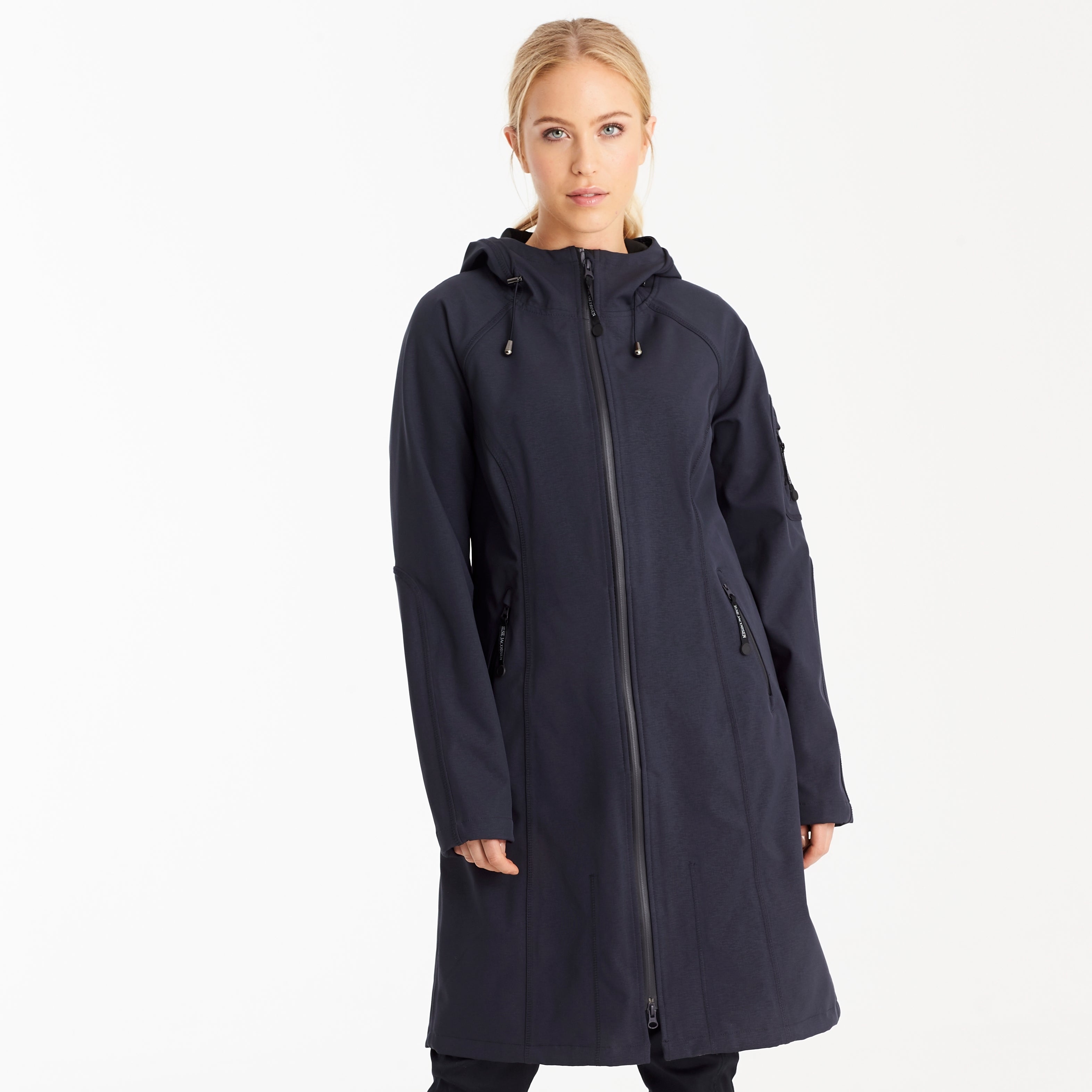 Woman modeling a dark navy Ilse Jacobsen Softshell raincoat; long sleeves, zip front, hood. Smooth, matte texture.