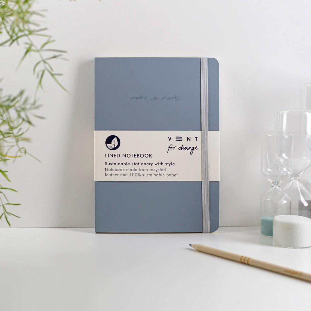Gray lined notebook with elastic closure; made from recycled leather and sustainable paper.