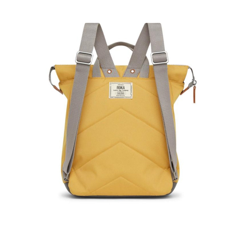 Mustard yellow quilted backpack with gray straps and a small brand label.