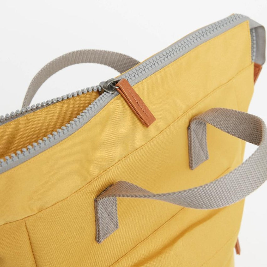 Mustard yellow canvas tote bag with gray straps and a tan zipper.