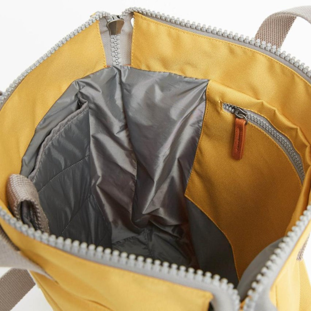 Mustard yellow tote bag with gray zipper and interior lining. Features a small zippered pocket inside.
