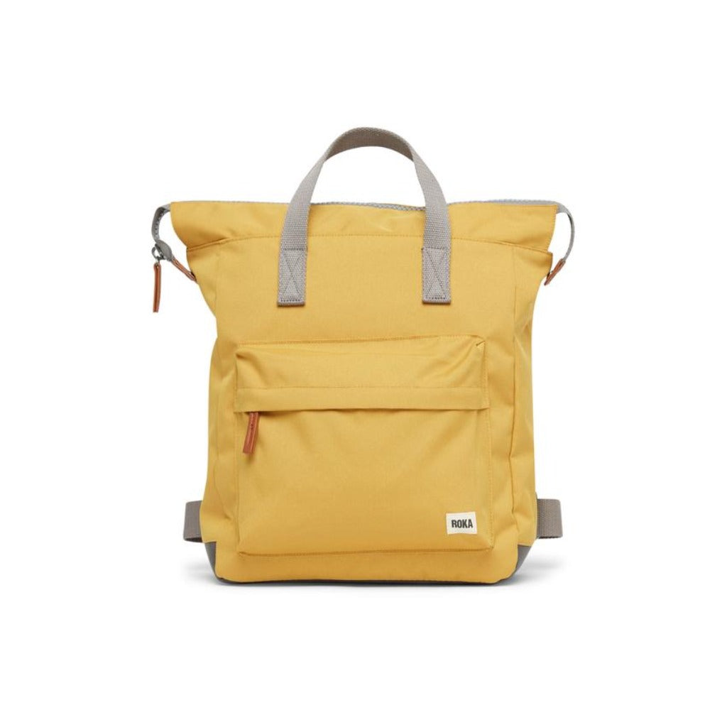 Mustard yellow rucksack with grey handles and straps, featuring a front pocket and small brand label.