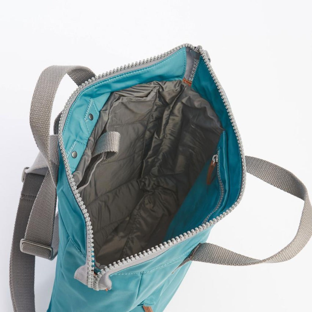 Teal nylon tote bag with gray straps and zipper closure; interior shows gray lining and pockets.