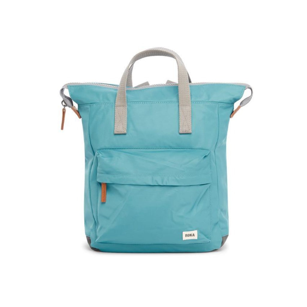 Teal blue Roka backpack with gray top handles and a smaller front pocket. Features tan zipper pulls.